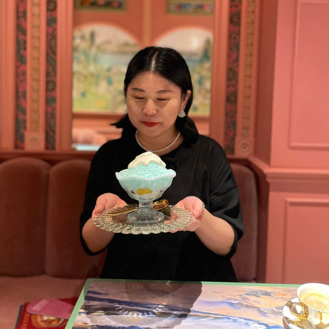 喫茶店のソファ席でかき氷を両手に持つ甲斐みのり氏