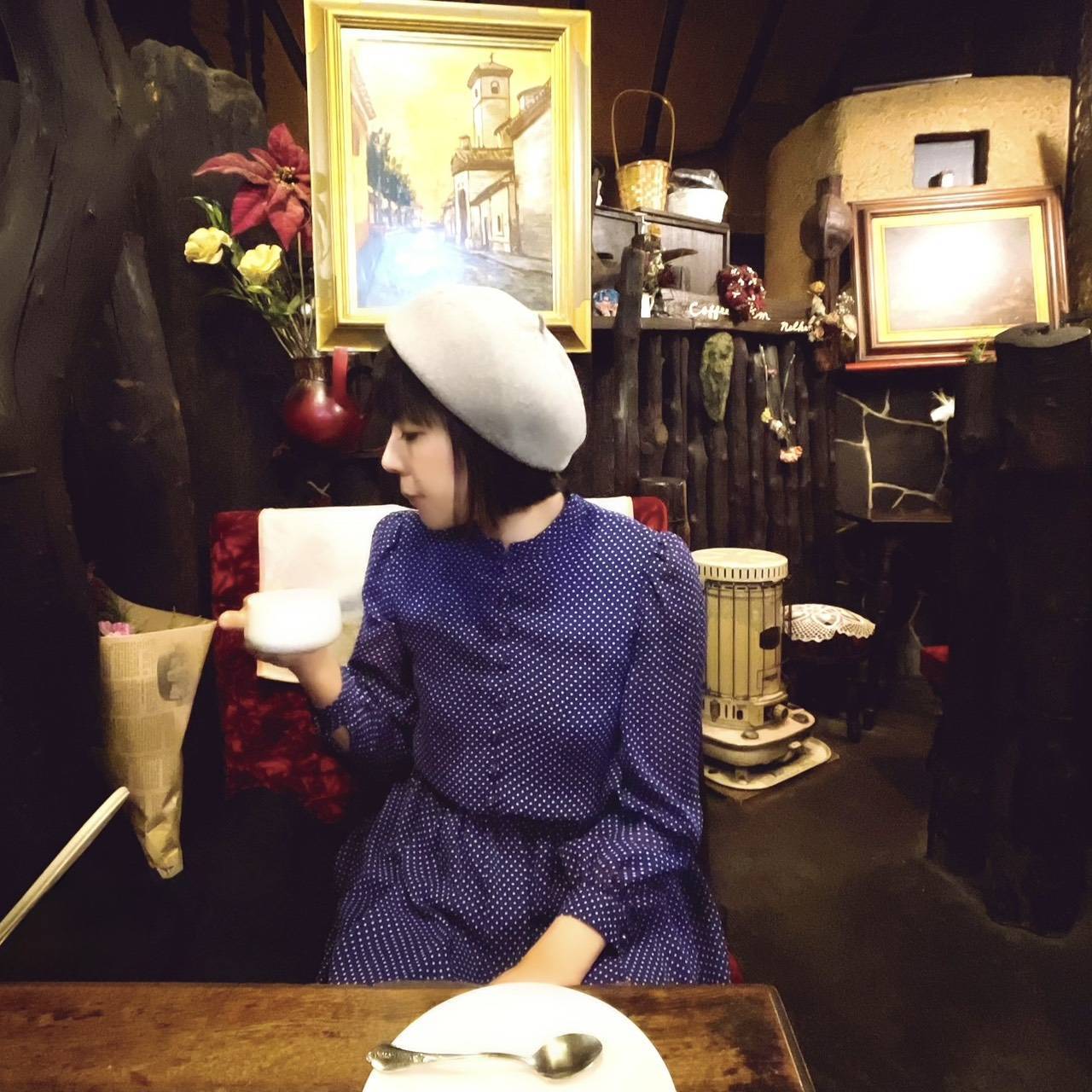レトロな喫茶店の席でカップを手にするベレー帽姿の難波里奈氏